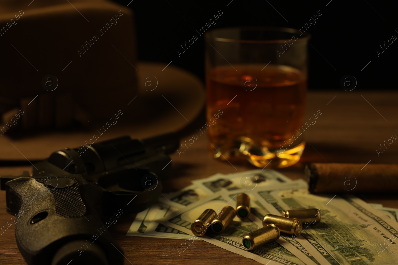 Mafia and criminal world. Gun, bullets, money, cigar, whiskey and hat on wooden table, closeup Photo of Mafia and criminal world. Gun, bullets, money, cigar, whiskey and hat on wooden table, closeup