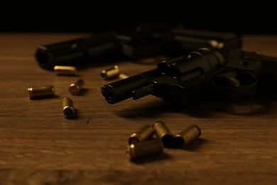 Photo of Mafia and criminal world. Guns with bullets on wooden table, closeup