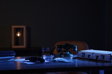 Photo of Gun, money, whiskey and other stuff on wooden table in mafia boss office