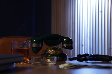 Photo of Gun, money, whiskey and other stuff on wooden table in mafia boss office