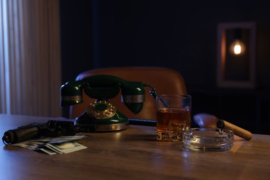 Photo of Gun, money, whiskey and other stuff on wooden table in mafia boss office