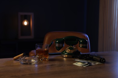 Photo of Gun, money, whiskey and other stuff on wooden table in mafia boss office