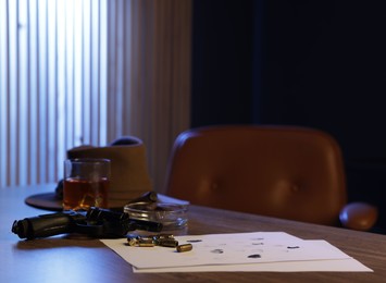 Photo of Gun, fingerprints, whiskey and other stuff on wooden table in mafia boss office