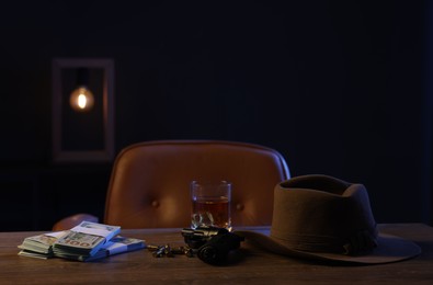 Photo of Gun, money, whiskey and other stuff on wooden table in mafia boss office