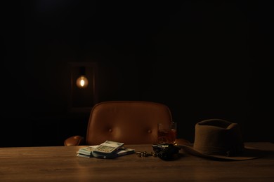 Photo of Gun, money, whiskey and other stuff on wooden table in mafia boss office