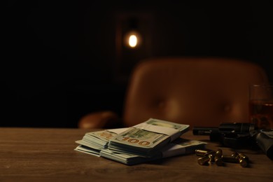 Photo of Gun, bullets and money on wooden table in mafia boss office. Space for text