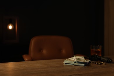 Photo of Gun, bullets, money and whiskey on wooden table in mafia boss office