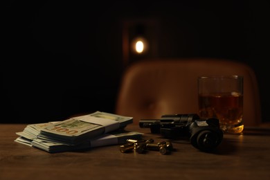 Photo of Gun, bullets, money and whiskey on wooden table in mafia boss office