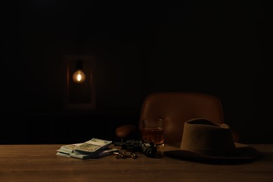 Photo of Gun, money, whiskey and other stuff on wooden table in mafia boss office. Space for text
