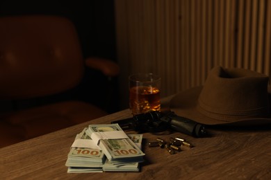 Photo of Gun, money, whiskey and other stuff on wooden table in mafia boss office. Space for text