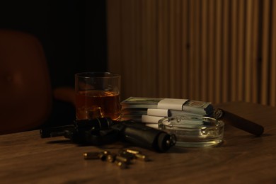 Photo of Gun, money, whiskey and other stuff on wooden table in mafia boss office
