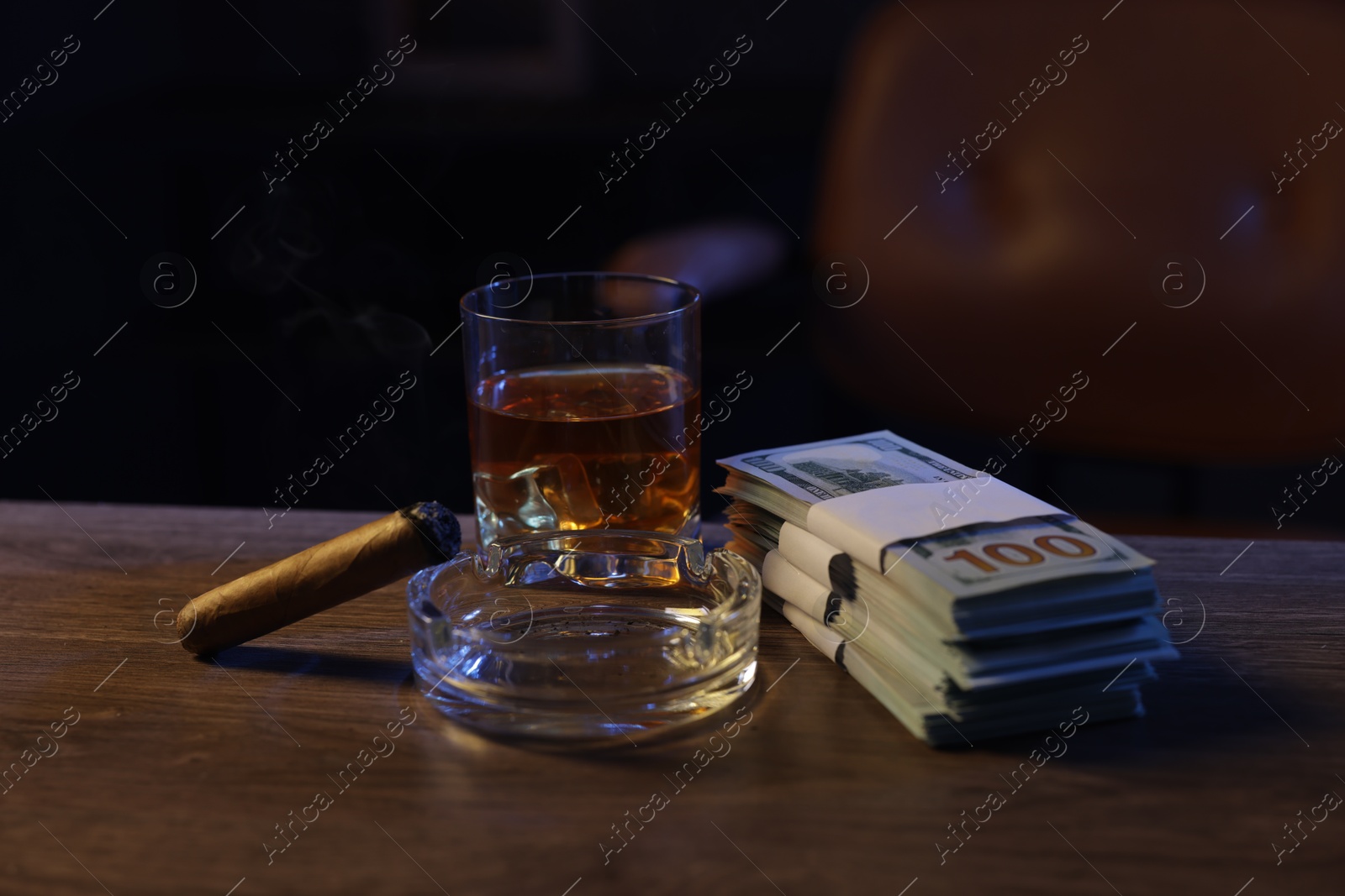 Ashtray with cigar, money and whiskey on wooden table in mafia boss office Photo of Ashtray with cigar, money and whiskey on wooden table in mafia boss office