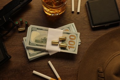 Photo of Mafia and criminal world. Money, bullets, whiskey, gun and hat on wooden table, flat lay
