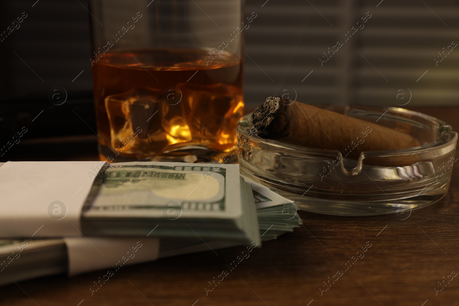 Mafia and criminal world. Money, ashtray with cigar and whiskey on wooden table, closeup Photo of Mafia and criminal world. Money, ashtray with cigar and whiskey on wooden table, closeup