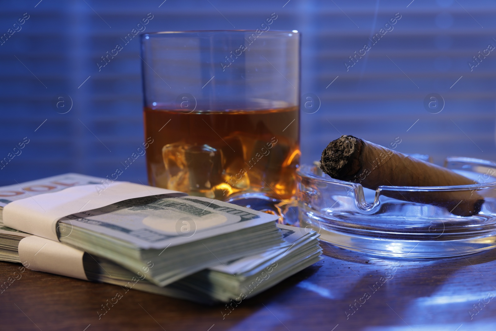 Mafia and criminal world. Money, ashtray with cigar and whiskey on wooden table, closeup Photo of Mafia and criminal world. Money, ashtray with cigar and whiskey on wooden table, closeup