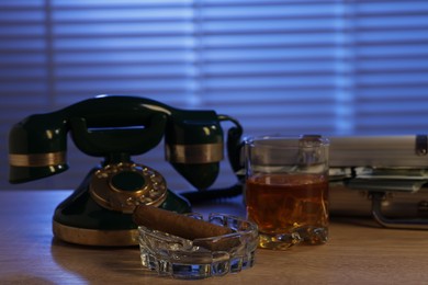 Photo of Mafia and criminal world. Money, whiskey, cigar and telephone on wooden table indoors