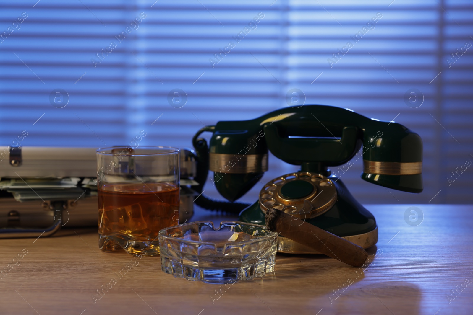 Photo of Mafia and criminal world. Money, whiskey, cigar and telephone on wooden table indoors