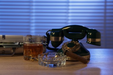 Photo of Mafia and criminal world. Money, whiskey, cigar and telephone on wooden table indoors