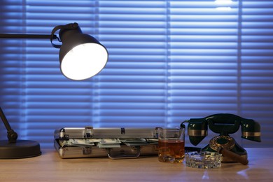 Photo of Mafia and criminal world. Money, whiskey, cigar and telephone on wooden table indoors
