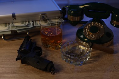 Photo of Mafia and criminal world. Money, whiskey, cigar and telephone on wooden table indoors