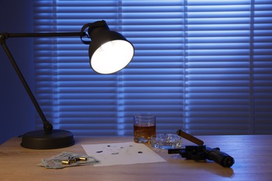 Photo of Mafia and criminal world. Gun, cigar, whiskey, fingerprints, money and bullets on wooden table indoors