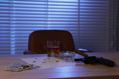 Photo of Mafia and criminal world. Gun, cigar, whiskey, fingerprints, money and bullets on wooden table indoors