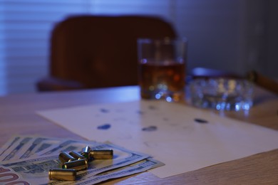 Photo of Mafia and criminal world. Money, bullets, cigar, whiskey and fingerprints on wooden table indoors, selective focus