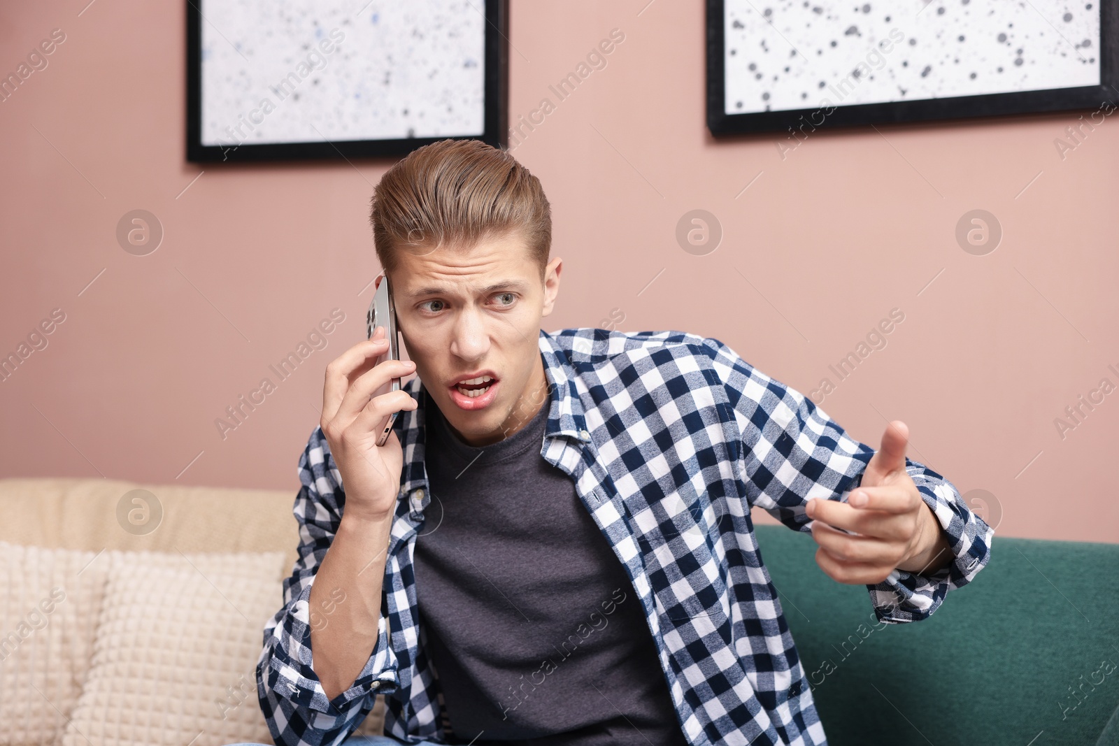 Photo of Young man complaining to someone via phone at home