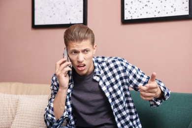 Photo of Young man complaining to someone via phone at home