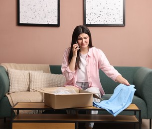 Photo of Young woman with package complaining to customer service via phone at home