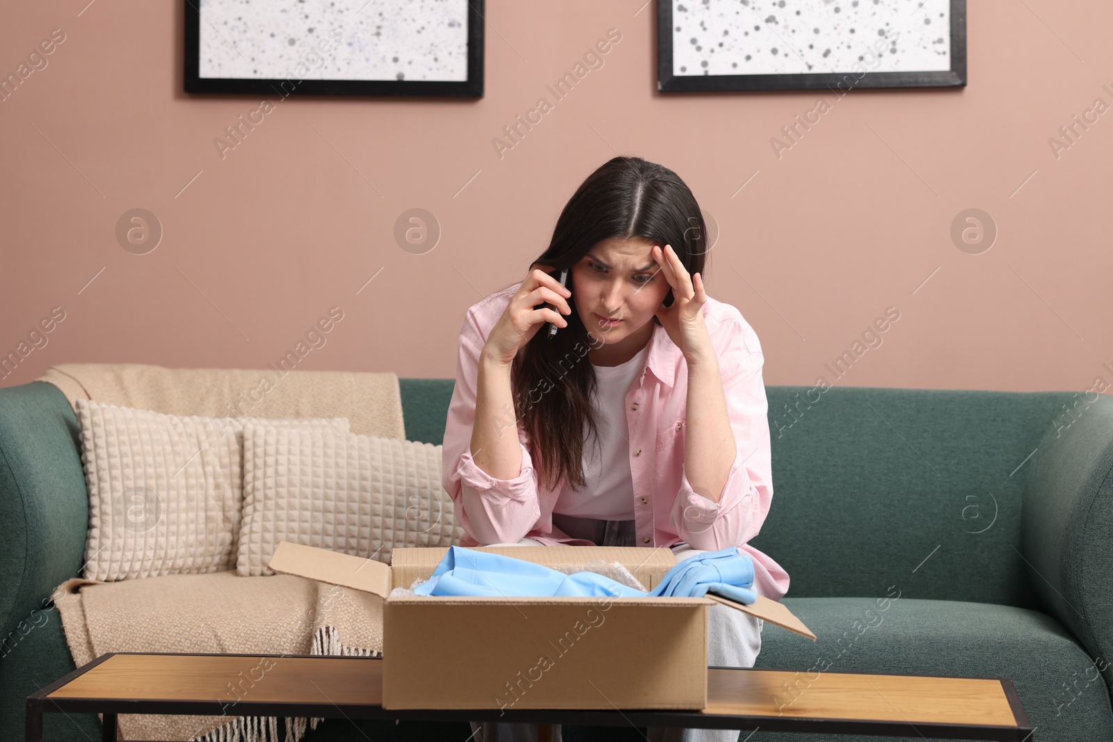 Photo of Young woman with package complaining to customer service via phone at home