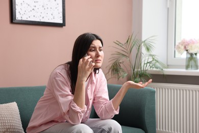 Photo of Young woman complaining to someone via phone at home