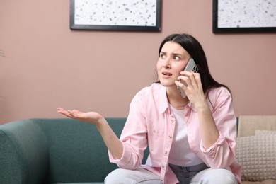 Photo of Young woman complaining to someone via phone at home