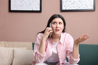 Photo of Young woman complaining to someone via phone at home