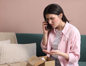 Photo of Young woman with package complaining to customer service via phone at home