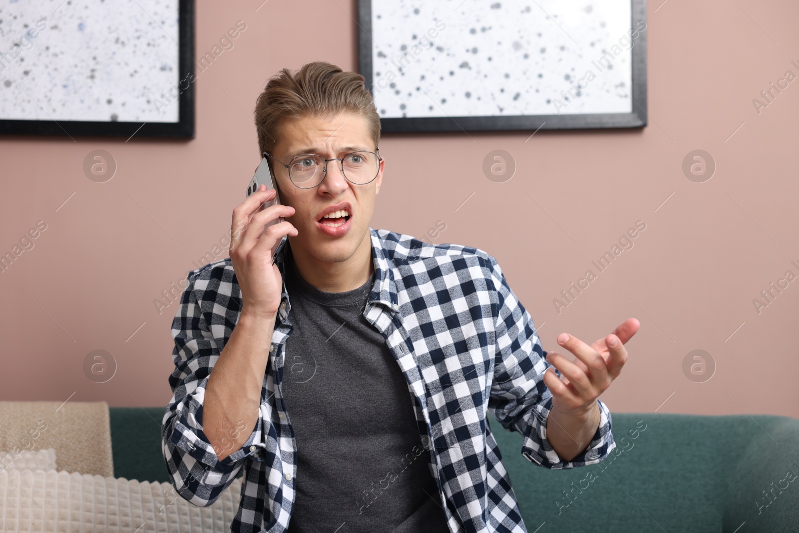 Photo of Young man complaining to someone via phone at home