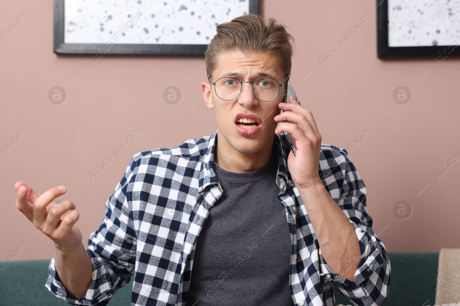 Photo of Young man complaining to someone via phone at home