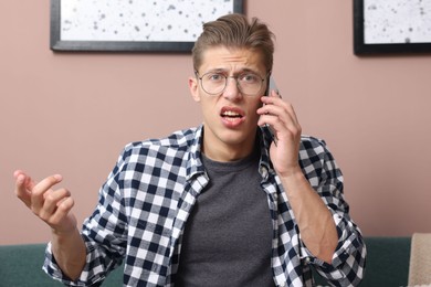 Photo of Young man complaining to someone via phone at home