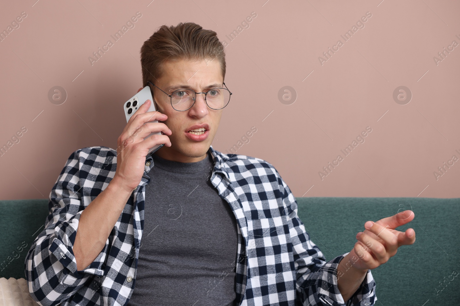 Photo of Young man complaining to someone via phone at home