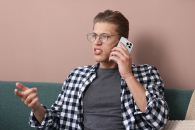 Photo of Young man complaining to someone via phone at home
