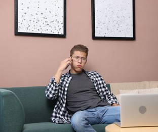 Photo of Young man complaining to someone via phone at home