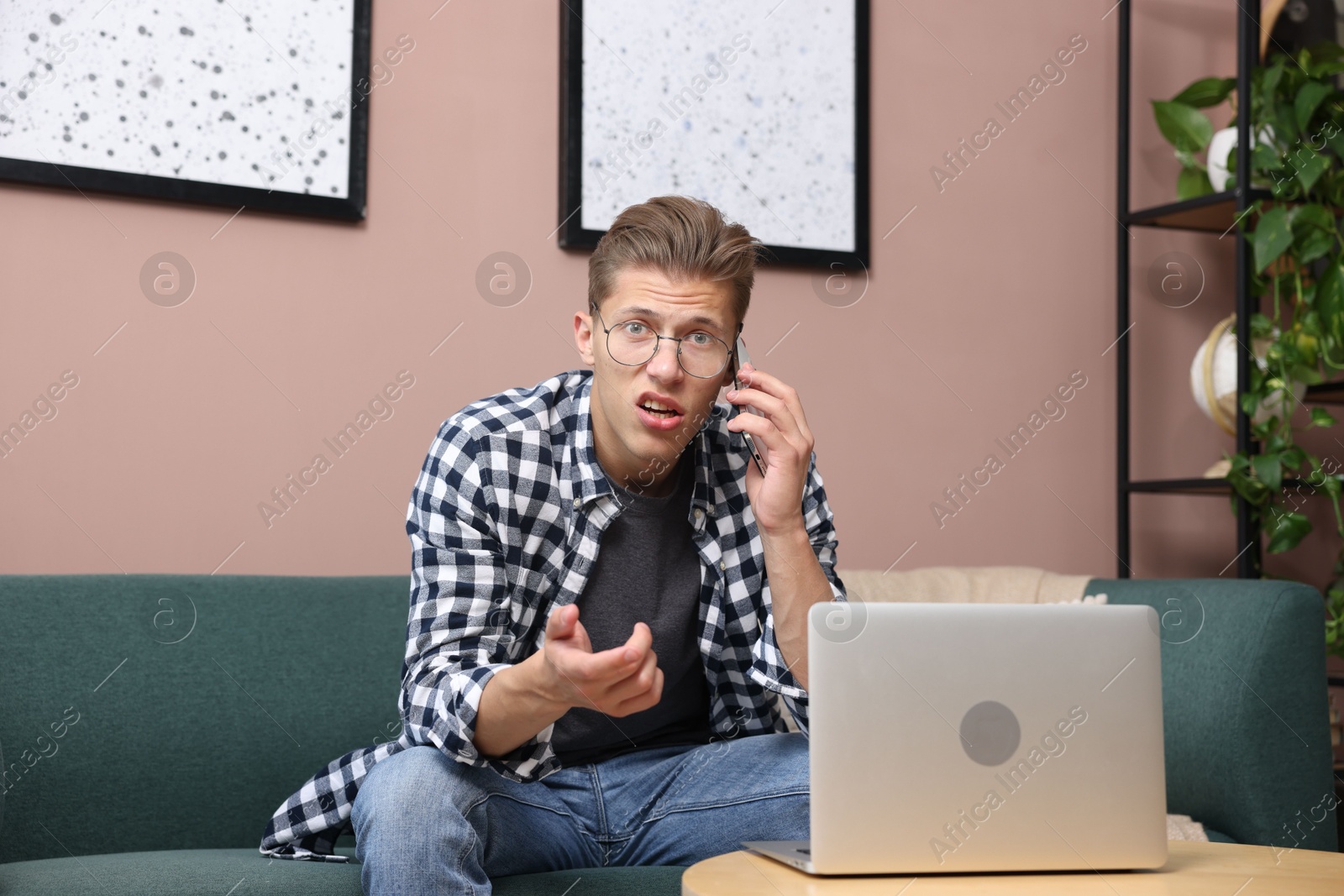 Photo of Young man complaining to someone via phone at home