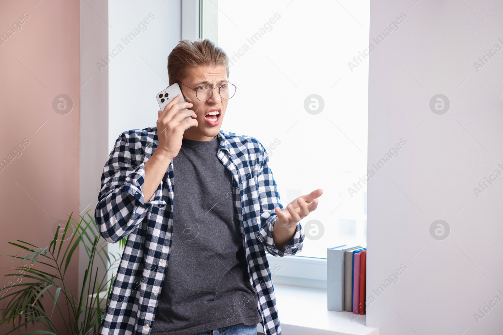 Photo of Young man complaining to someone via phone at home