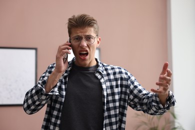 Photo of Young man complaining to someone via phone at home