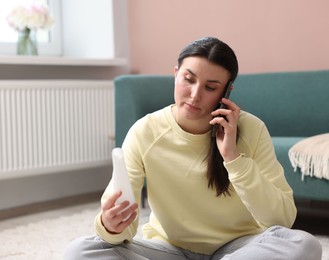 Photo of Young woman with product complaining to customer service via phone at home