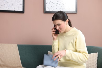 Photo of Young woman with bag complaining to customer service via phone at home