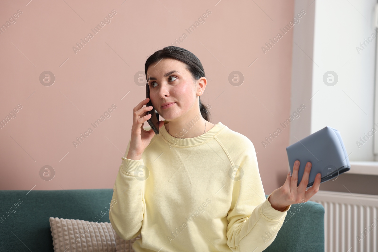 Photo of Young woman with bag complaining to customer service via phone at home
