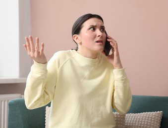 Photo of Young woman complaining to someone via phone at home