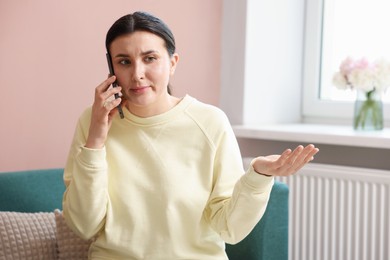 Photo of Young woman complaining to someone via phone at home