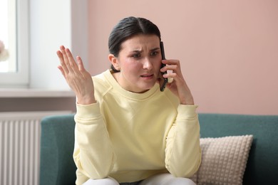 Photo of Young woman complaining to someone via phone at home